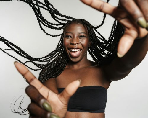 Black woman with afro pigtails laughing and gesturing at camera
